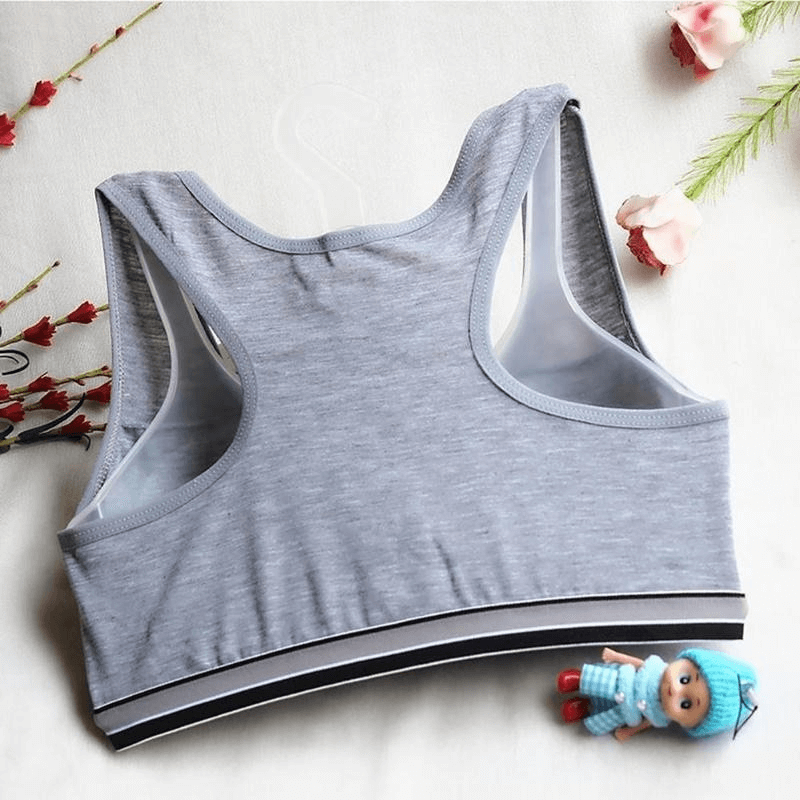 Gray sports quick-drying elastic top-bra with lining, perfect for fitness, paired with a cute knitted doll on a floral background.